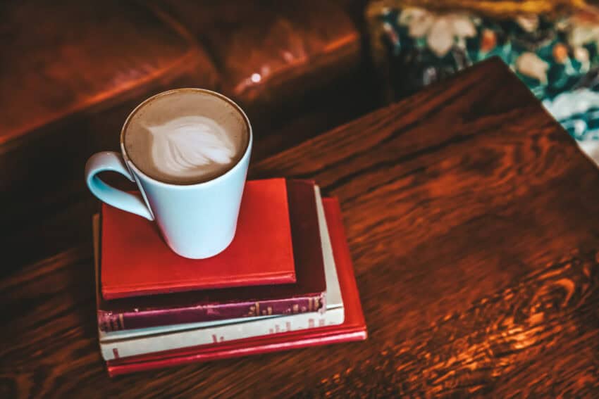 coffee shop cafe latte on stack red books wood table.